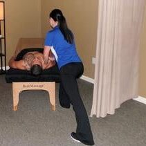 A woman is standing over a man on the massage table.